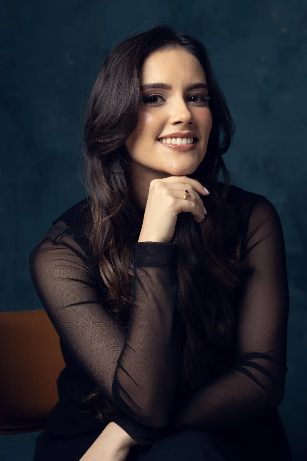 Dra. Mariana Regilio sorrindo, com a mão apoiada no queixo